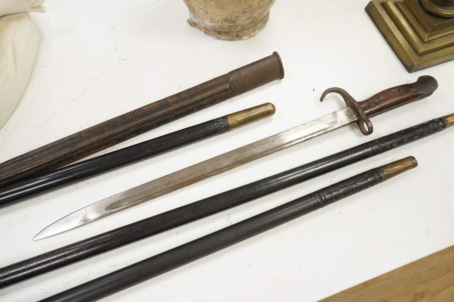 Three early 20th century Indonesian bone overlaid sword sticks and a bayonet, largest 92cm in length